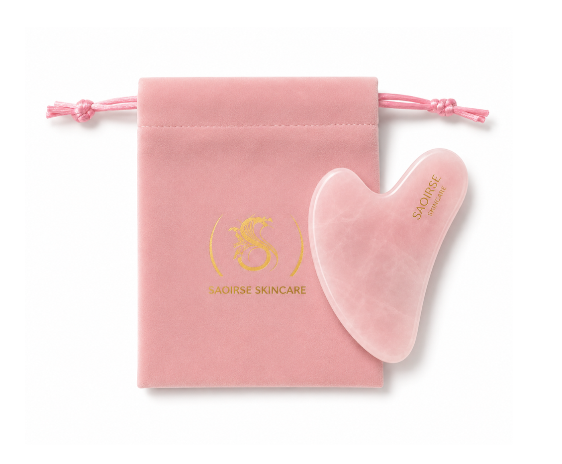 Pink velvet drawstring pouch with gold logo next to a pink heart-shaped gua sha tool from Saoirse Skincare.