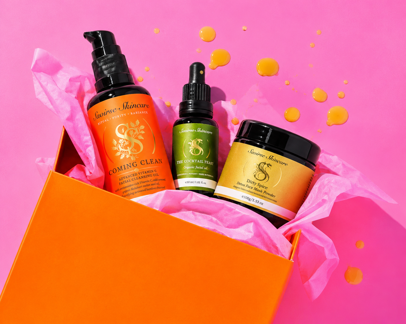 Open orange gift box with three skincare bottles on pink background; includes cleanser, serum, and face mask powder from Saoirse Skincare list.